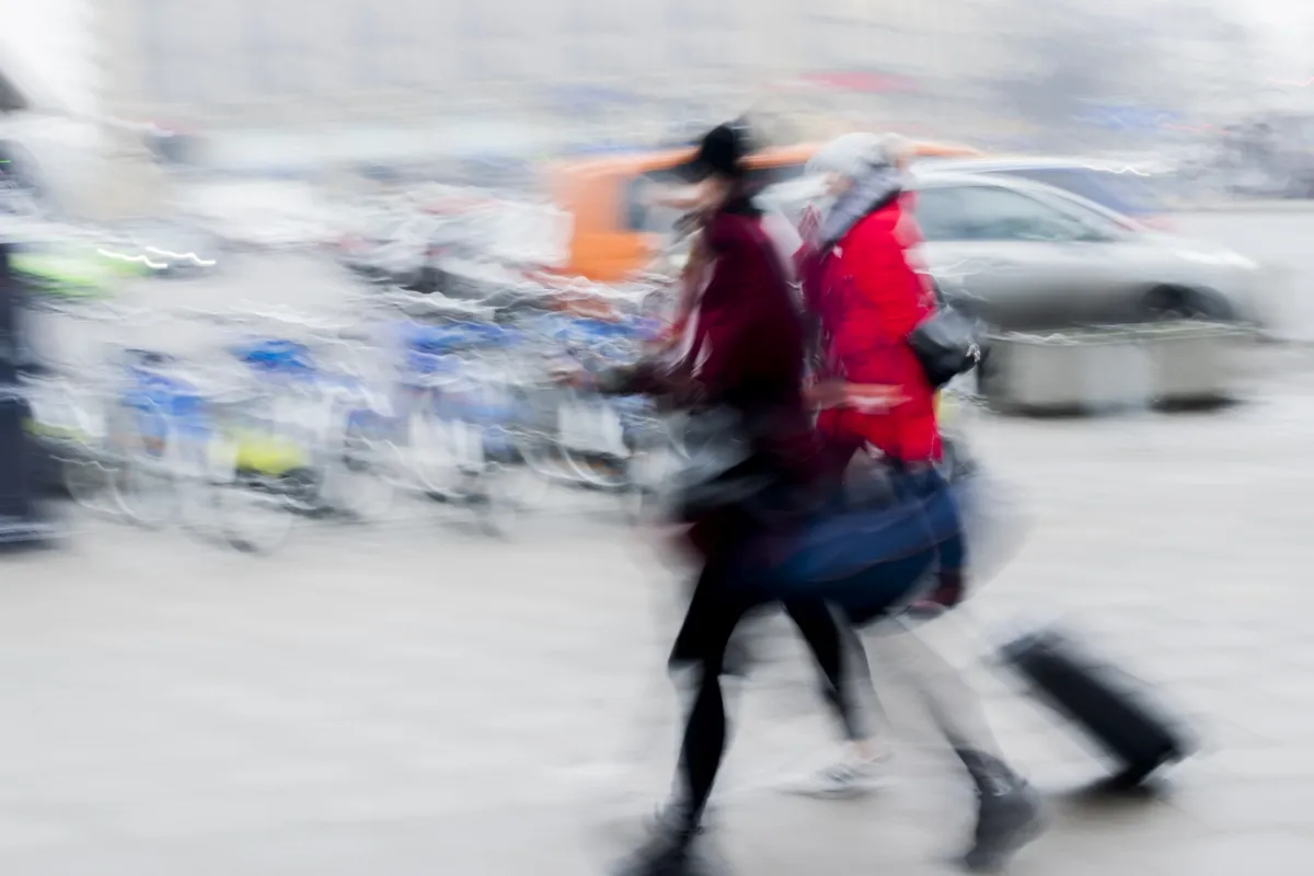 Two women blurred past parked bicycles, one wearing a bright red coat